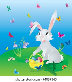 easter hare on the green grass under blue sky with eggs in basket and butterflies around