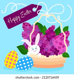 Easter holiday basket with lilac branches, bunny and Easter eggs on a plain blue background