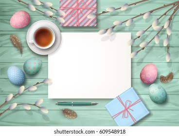 Easter holiday top view wooden background with gifts, pen, blank paper sheet, cup of tea, eggs, pussy willow branches, feathers.