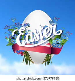 Easter lettering  greeting card with egg and forget-me-not flowers on blue sky background. Easter greetings. Easter lettering background with spring flowers.