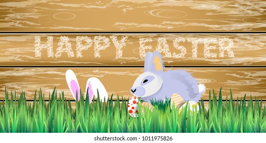 Easter. Rabbit easter in the grass on a background of a wooden fence in Easter eggs. horizontal sheet orientation