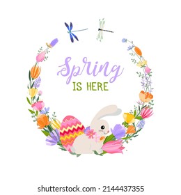 Easter spring greeting card. A wreath of spring flowers and herbs with bright Easter eggs, a cute bunny and dragonflies. Inscription Spring is here.