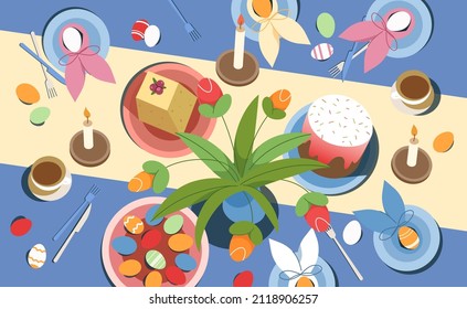 Vista de la cima de la mesa de Semana Santa con pasteles tradicionales de vacaciones y postre con cuajada dulce sobre manteles azules. Orejas de conejo con huevos pintados de colores en platos de estilo lao plano. Concepto de celebración de primavera.