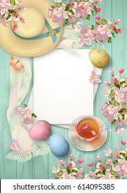 Easter top view background with painted eggs, blank sheets of paper, straw hat, blossoming tree branches, glass teacup and butterfly