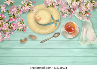 Easter top view wooden background with a straw hat, blossoming tree branches, feathers, glass teacup and butterfly