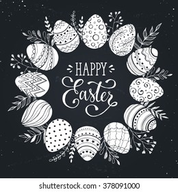 Easter wreath with easter eggs hand drawn on chalk board. Decorative doodle frame from Easter eggs and floral elements. Easter eggs with ornaments in circle shape.