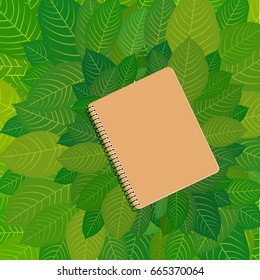 Eco-cardboard notebook framing green leaves. Educational theme. Natural resources. Ecological production