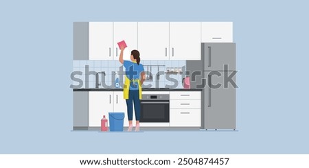 Efficient housewife cleaning the kitchen, she is rubbing the cabinets with a sponge