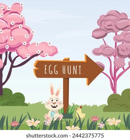 Egg hunt. Bunny outdoor sitting in the grass among flowers hugging Easter egg and little chick walking near by. Pink trees and clear blue sky on the background