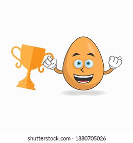 Personaje de mascota de huevo con un trofeo en la mano derecha. ilustración vectorial