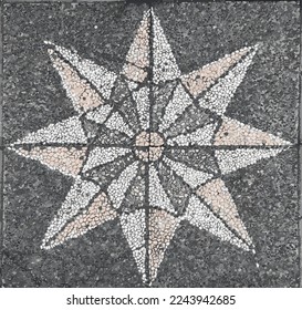 Eight edged star like mosaic pebble inlay on a pavement in Ubud