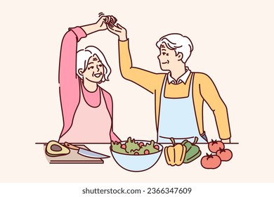 Ancianos, un par de veganos cocinan juntos la cena y el baile, pidiendo un estilo de vida saludable y renunciando a la carne. Hombre y mujer en edad de jubilarse, se han convertido en veganos en un aumento de fuerza y energía