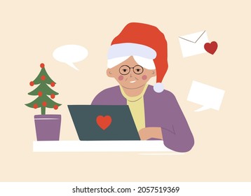 An elderly grandmother in a Santa Claus hat writes Christmas greeting messages online. Communication over the Internet at a distance. 