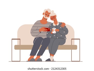 Elderly happy couple sitting on a sofa and watching phone.