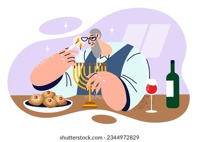 Elderly jewish man lights candles in minor before dinner and prepares to celebrate Hanukkah or Purim. Gray-haired lonely retired jew performs traditional ritual, celebrating religious holiday alone