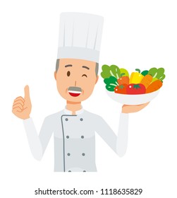 An elderly male chef wearing a cook coat has vegetables