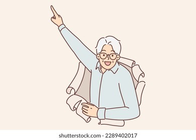 Elderly man peeks out of hole in paper and points finger upwards, paying attention to promo offers. Elderly businessman recommends looking up making gesture drawing attention to important information 