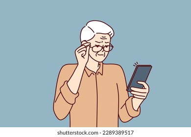 Elderly man with poor eyesight squint looking at screen of mobile phone to read SMS. Grandpa is having vision problems due to cataracts in eyes and needs help of ophthalmologist doctor 