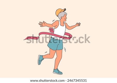 Elderly man runner with finishing tape wins running marathon among athletes of age category. Grandfather participates in marathon and leads active lifestyle after retirement to avoid health problems