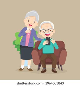 Elderly man and woman sitting on sofa and looks at phone in the living room