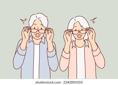 Elderly surprised couple takes off glasses and looks at screen after learning about big promotions and sales for shopping. Surprised grandparents shout wow and feel excited about unexpected news