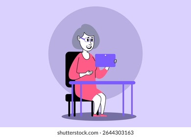 Elderly woman with gray hair sitting at table, wearing dress. Woman engaged with tablet, smiling and enjoying her moment indoors