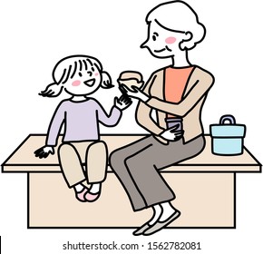 Elderly woman and her grandchild sitting together on bench, have lunch. Grandma and granddaughter sitting on bench and eating sandwiches. Grandmother and little girl eating food together outdoors.