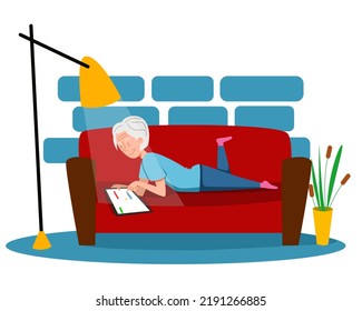 An elderly woman is lying on the couch and playing on a tablet.