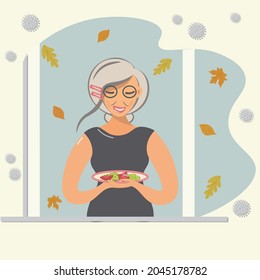 An elderly woman in quarantine stands at a window in late fall. A lovely lady holding a plate of salad. She loves a healthy and nutritious diet of fruits and vegetables. Vector flat cartoon style.