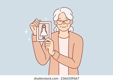 Elderly woman shows photo of little girl and smiles, nostalgic and remembering past. Grandmother demonstrates photography of granddaughter and wishes to become young, experiencing nostalgic feelings