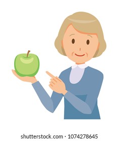 An elderly woman wearing blue clothes has a green apple
