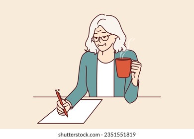 Elderly woman is writer, drinking coffee and sitting at table, inventing new book of bestseller and writing down text on paper. Grandmother with pen smiles and writes will or makes legal deal