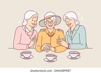 Elderly women drink tea and laugh, rejoicing at long-awaited meeting, dressed in elegant clothes. Tea party of old girlfriends reminiscing funny stories from past or planning upcoming trip