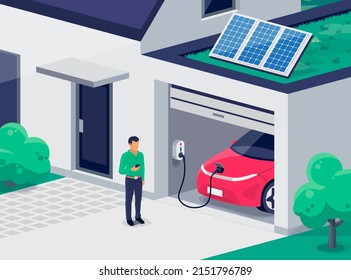 Electric car parking charging inside home garage and green roof wall box charger station. Man standing with smartphone near family house building with clean renewable energy photovoltaic solar panels.