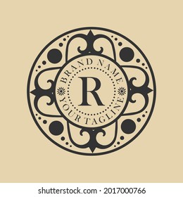 An elegant circle monogram logo featuring the letter "R" surrounded by royal ornamental flourishes and decorative elements, possibly including a crown or vintage frame. Ideal for luxury branding,
