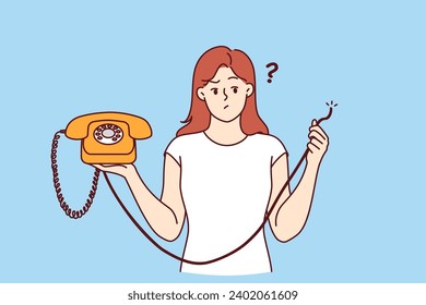 Embarrassed woman is holding retro telephone with torn wire, and is wondering how to restore telephony to call friends. Girl was left without communication due to broken telephone and needs repairman