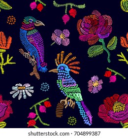 Embroidered texture inspired by folk art. Seamless vector pattern with birds, branches and flowers. Vintage motifs. Retro textile design collection. Colorful on dark.