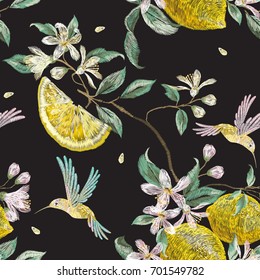 Embroidery fashion seamless pattern with hummingbird and lemon flowers. Vector embroidered floral ornament with bird on black background for clothing design.