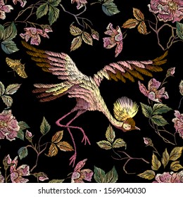 Bordado, sin fisuras, de estampado floral con rosas silvestres y grúas. Ramo vectorial tradicional bordado con flores sobre fondo negro para el diseño de ropa.