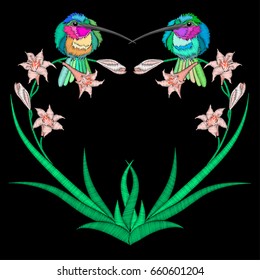 Embroidery with symmetrical birds and lily in form heart frame. Hummingbird sitting on flowers isolated on black background.