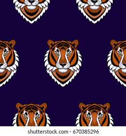 Embroidery tiger colorful head seamless pattern on blue background. Wallpaper with needlework animal sign.