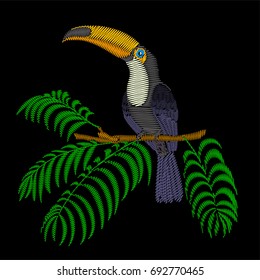 Embroidery toucan bird sitting on tree branch with palm like leaves.