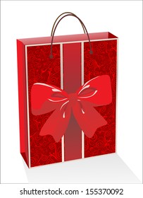 Empty glossy red gift bag decorated with ribbons and a bow, isolated on white