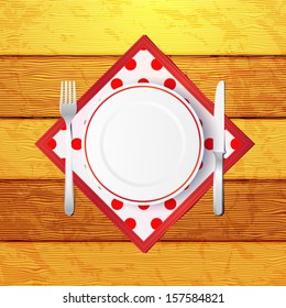 Empty plate with fork and knife on a wooden table