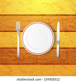 Empty plate with fork and knife on a wooden table