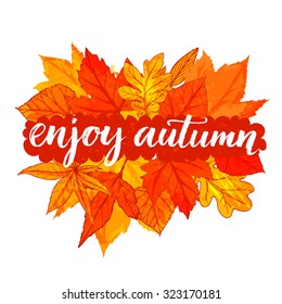 Enjoy autumn - inspirational calligraphy on banner with yellow and orange leaves. Vector lettering for cards, prints and social media content.