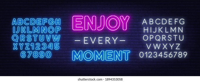 Enjoy every moment neon inspirational quote on a brick wall.