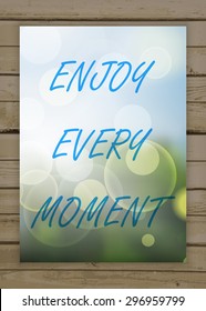 Enjoy every moment on the natural blurry background. Typography on beautiful colorful background with bokeh.