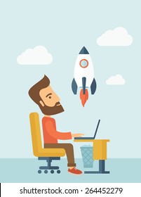 An enthusiastic, eager hipster Caucasian young man with beard sitting in front of his laptop browsing, researching  and planning a metaphor for new business. On-line start up business concept. A