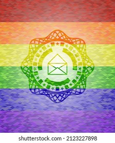 icono de sobre dentro del emblema sobre fondo de mosaico con los colores de la bandera LGBT. 